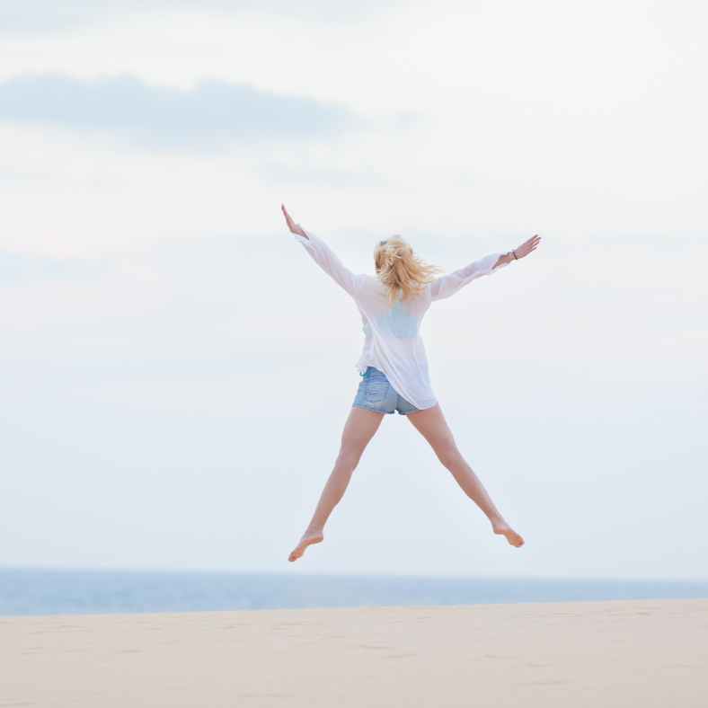 Blond woman jumping on a beach